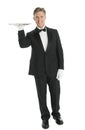 Portrait Of Confident Waiter Carrying Tray Over White Background