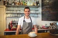 Portrait of confident waiter with coffee at counter in cafe Royalty Free Stock Photo