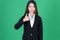 Portrait of confident young Asian business woman giving thumbs up sign as sign of success over green isolated background Royalty Free Stock Photo