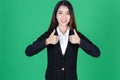 Portrait of confident young Asian business woman giving thumbs up sign as sign of success over green isolated background Royalty Free Stock Photo