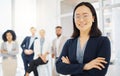 Portrait of a confident young asian businesswoman wearing glasses and standing with her arms crossed in an office with Royalty Free Stock Photo