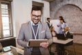 Confident young businessman using digital tablet while colleague in background Royalty Free Stock Photo