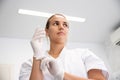 Portrait of confident young female dentist putting on gloves