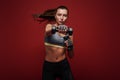 Never stop! Sportswoman is exercising with dumbbells standing over red background Royalty Free Stock Photo