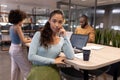 Portrait of confident young hispanic businesswoman leaning on desk against biracial colleagues Royalty Free Stock Photo