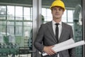 Portrait of confident young male architect holding rolled up blueprints in industry Royalty Free Stock Photo