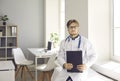 Portrait of confident young male doctor standing in office of modern medical center. Royalty Free Stock Photo