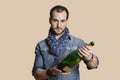 Portrait of a confident young man with champagne bottle over colored background Royalty Free Stock Photo