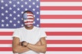 Portrait of confident Young man with painted face against American flag Royalty Free Stock Photo