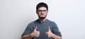 Portrait of confident young man showing thumbs up, over white background. Wearing glasses and grey sweater Royalty Free Stock Photo