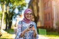 Portrait of confident young woman wearing hijab standing with mobile phone Royalty Free Stock Photo