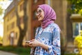 Portrait of confident young woman wearing hijab standing with mobile phone Royalty Free Stock Photo