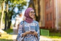 Portrait of confident young woman wearing hijab standing with mobile phone Royalty Free Stock Photo