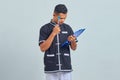 Portrait of confused asian young man wearing karate uniform holding clipboard and pen with pen Royalty Free Stock Photo