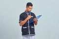 Portrait of confused asian young man wearing karate uniform holding clipboard and pen with pen Royalty Free Stock Photo