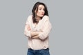 Portrait of confused beautiful attractive brunette woman in casual striped orange shirt and curly hairstyle standing crossed arms Royalty Free Stock Photo