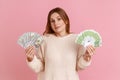 Rich blond woman holding two big fan of euro and dollar banknotes, dont know how to spend money. Royalty Free Stock Photo