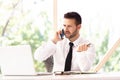 Portrait of confused businessman making a business call and using laptop while working in the office Royalty Free Stock Photo