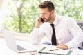 Portrait of confused businessman making a business call and using laptop while working in the office Royalty Free Stock Photo