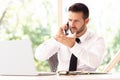 Portrait of confused businessman making a business call and using laptop while working in the office Royalty Free Stock Photo