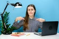 Portrait of confused employee business woman 20s old years in shirt sit work at white office desk with laptop point index fingers