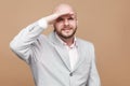 Portrait of confused handsome middle aged bald bearded businessman in classic light gray suit standing and looking too far with g Royalty Free Stock Photo