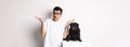 Portrait of confused hipster guy dog owner shrugging, standing near cute black pug pet, white background Royalty Free Stock Photo