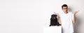 Portrait of confused hipster guy dog owner shrugging, standing near cute black pug pet, white background Royalty Free Stock Photo