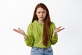 Portrait of confused redhead girl asking whats wrong, cant understand something, looking concerned and puzzled, standing