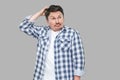 Portrait of confused or thoughtful handsome middle aged business man in casual checkered shirt standing touching his head and Royalty Free Stock Photo