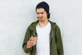 Portrait of confused unsatisfied hipster standing isolated over white wall outdoors, holding papercup with drink, undelighted with