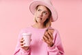 Portrait of confused woman in hat holding smartphone and coffee cup Royalty Free Stock Photo
