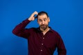 Portrait of a confused young man scratching his head isolated over blue background Royalty Free Stock Photo