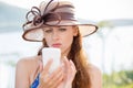 Portrait of confused young woman in hat looking at phone, reading unpleassnt text message. Human emotion reaction face expression Royalty Free Stock Photo