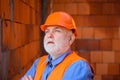Portrait of construction worker in safety vest and hard hat at work. Bearded architect builder in protective helmet