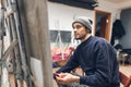 Portrait of a contemporary young man painting a picture at a workshop in painting, holding a brush in his hands and looking at the Royalty Free Stock Photo