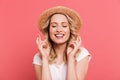 Portrait of content blond woman 20s wearing straw hat keeping fingers crossed and wishing for luck Royalty Free Stock Photo