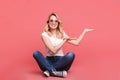 Portrait of content blond woman 20s wearing vintage sunglasses laughing while sitting on floor with legs crossed Royalty Free Stock Photo