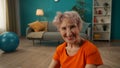 Portrait of a contented smiling elderly woman in the living room close up. A grayhaired retired woman, tired, but