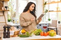 Portrait of cooking healthy food young woman in kitchen looking for a recipe on the Internet. Using tablet computer Royalty Free Stock Photo