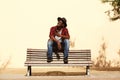 Cool african guy in hat sitting on bench by the street Royalty Free Stock Photo