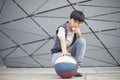 Portrait of cool Asian kid holding basketball outdoors
