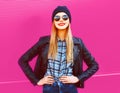 Portrait cool blonde smiling girl in rock black style jacket, hat posing on city street over colorful pink wall Royalty Free Stock Photo