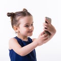 Portrait of cool cheerful little girl taking photo with smart phone. Cute kid shooting selfie on front camera isolated on white Royalty Free Stock Photo