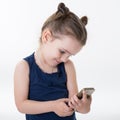 Portrait of cool cheerful little girl taking photo with smart phone. Cute kid shooting selfie on front camera isolated on white Royalty Free Stock Photo