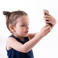 Portrait of cool cheerful little girl taking photo with smart phone. Cute kid shooting selfie on front camera  on white Royalty Free Stock Photo