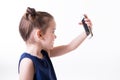 Portrait of cool cheerful little girl taking photo with smart phone. Cute kid shooting selfie on front camera  on white Royalty Free Stock Photo