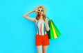 Portrait cool girl blowing red lips sends air kiss posing with shopping bags in colorful t-shirt, summer straw hat on blue Royalty Free Stock Photo