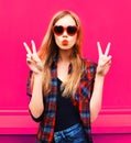 Portrait cool girl in heart shaped sunglasses sending sweet air kiss on colorful pink