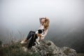 Portrait cool Girl hug dog border collie on edge of rock in fog in mountain smiling Royalty Free Stock Photo